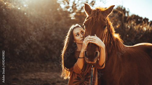 Chica joven andaluza ecuestre montando sobre caballo marron en un campo natural sin silla ni riendas en el sur de españa al atardecer feliz