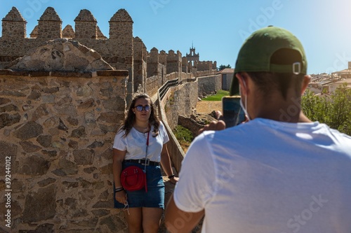 selective focus of a boy photographing a girl on top of the wall of the Avila fortress in Spain photo