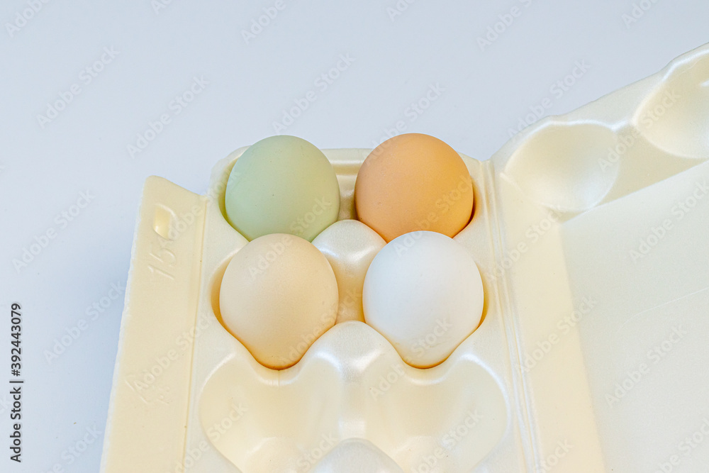 Fototapeta premium Multicolored chicken eggs lie in foam containers for storage and carrying on a light background. Close up. Soft focus