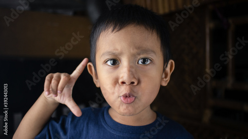 Portrait of exited asian boy with his thumb and index finger up
