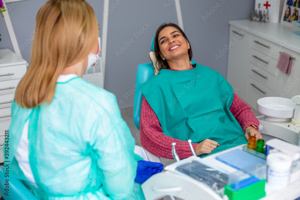 Female dentist in the dental office talking with female patient and preparing for treatment.
