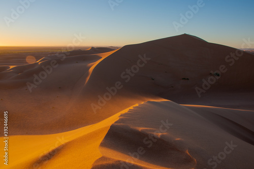 Wide angle shoot of sand desert dunes of Erg Chigaga moved by the wind. The gates of the Sahara  at sunrise. Morocco. Concept of travel and adventure