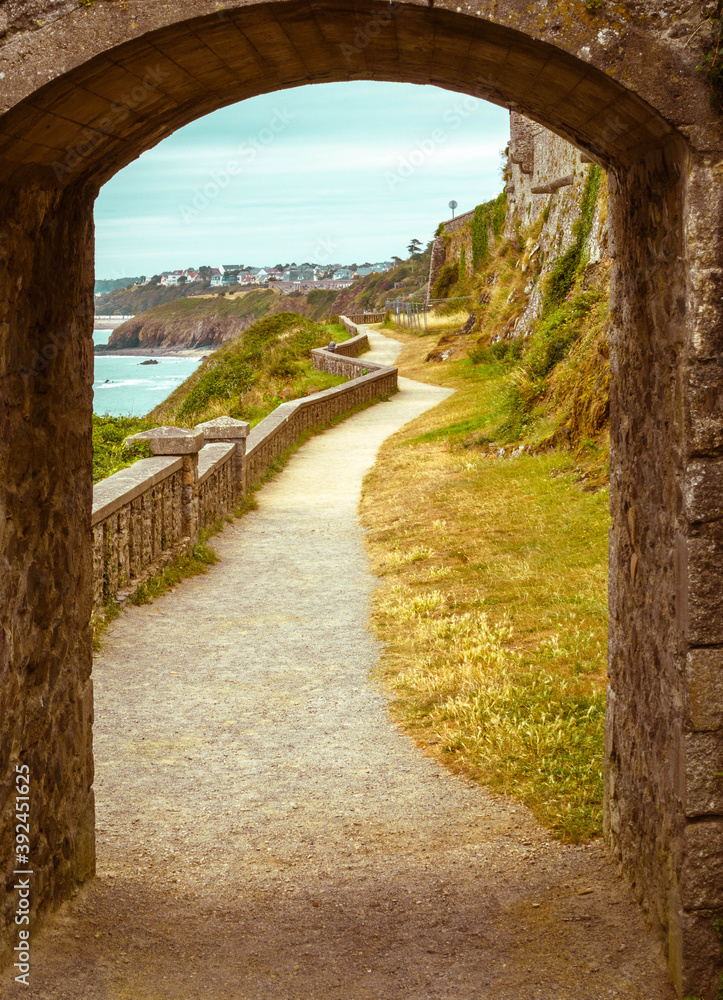 Obraz premium walking path, trail through arched stone door on a beach