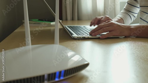 Selective focus at men hand and keyboard. Blurred internet router on working table with man typing on computer laptop. Fast and high speed internet connection from fiber line with LAN cable connection