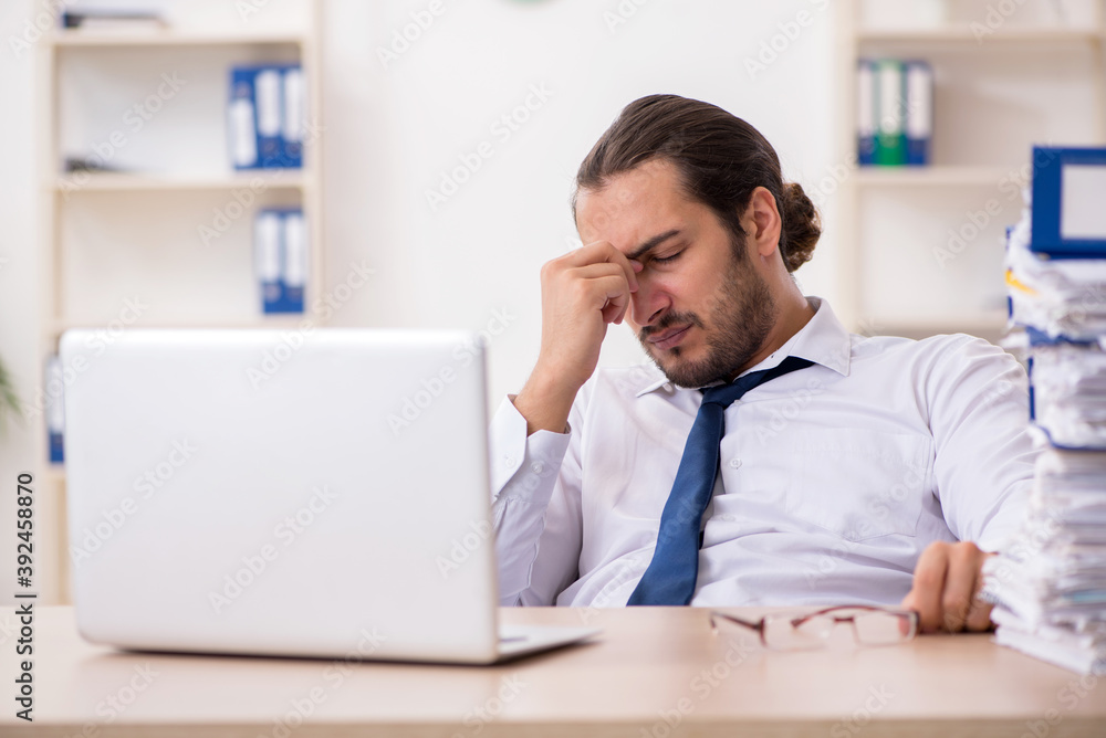 Young businessman unhappy with excessive work in the office Young businessman unhappy with excessive work in the office