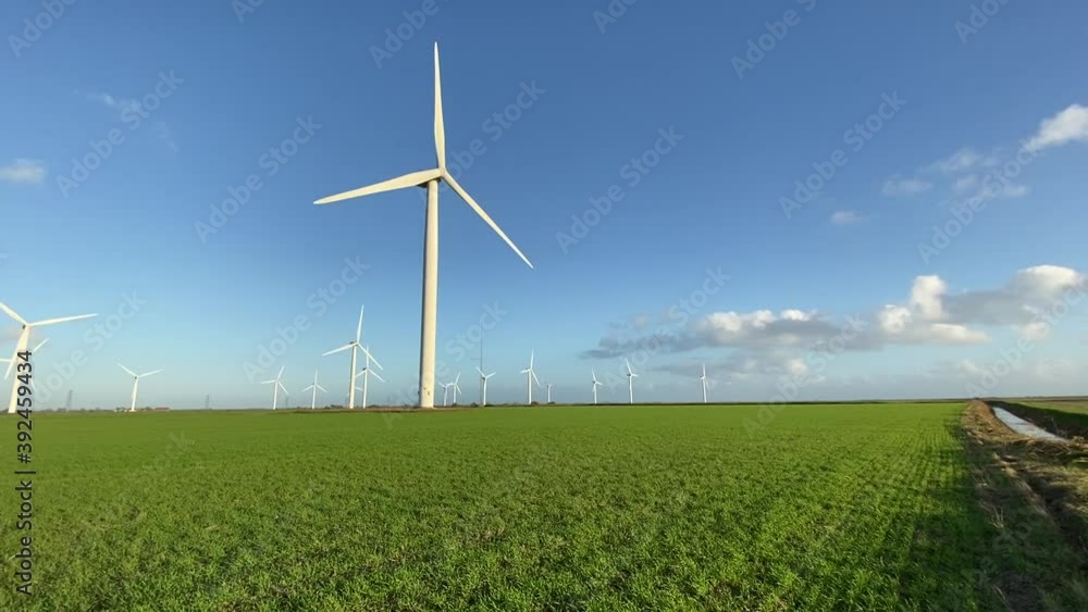 Wind farm turbines that produce electricity energy. Windmill Wind power technology productions Wind turbines standing in green field - stock video footage