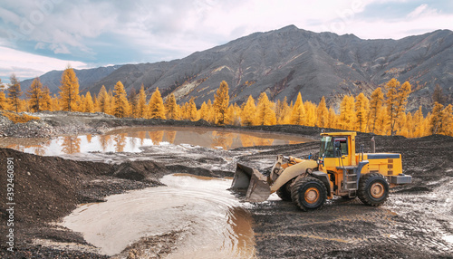Wheel loader at work. It transports gold-bearing mountain soil to the hopper of the washing device. The gold mining industry in Eastern Siberia widely uses such equipment as front loader, bulldozer,  photo