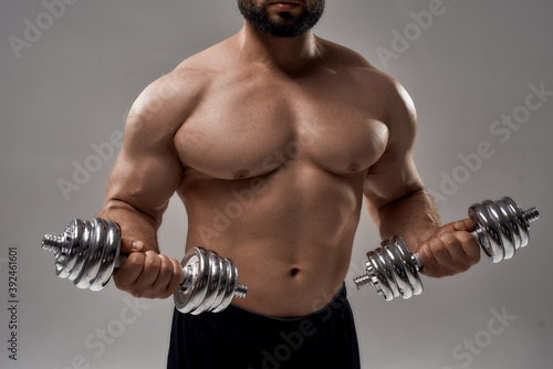 Figure of young muscular caucasian sportsman lifting dumbbells