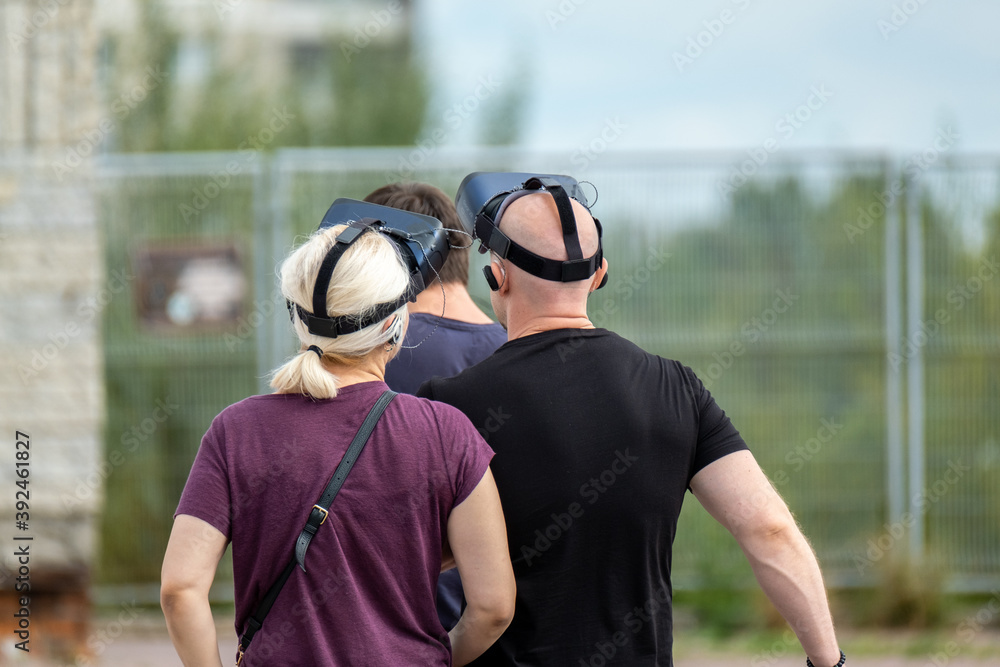 Naklejka premium Unrecognizable people in VR goggles on street