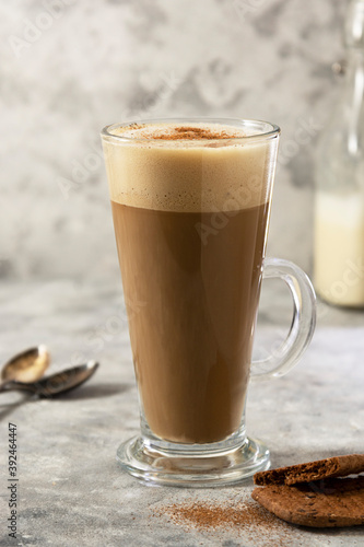Coffee drink with whipped milk in tall glass cup with cinnamon.