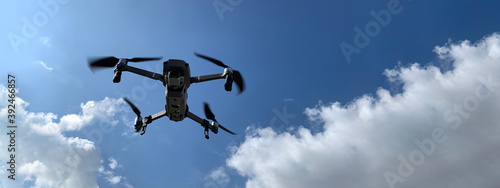 Ultra wide panoramic photo of latest technology RC camera drone or UAV (unmanned aerial vehicle) hovering on deep blue cloudy sky