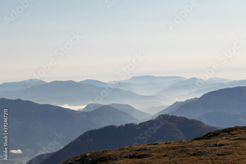 Fototapeta Naklejka Na Ścianę i Meble -  A panoramic view on the plain on top of a mountain in Hochschwab region in Austrian Alps. The flora overgrowing the slopes is turning golden. The valley is shrouded in fog. Mysterious landscape