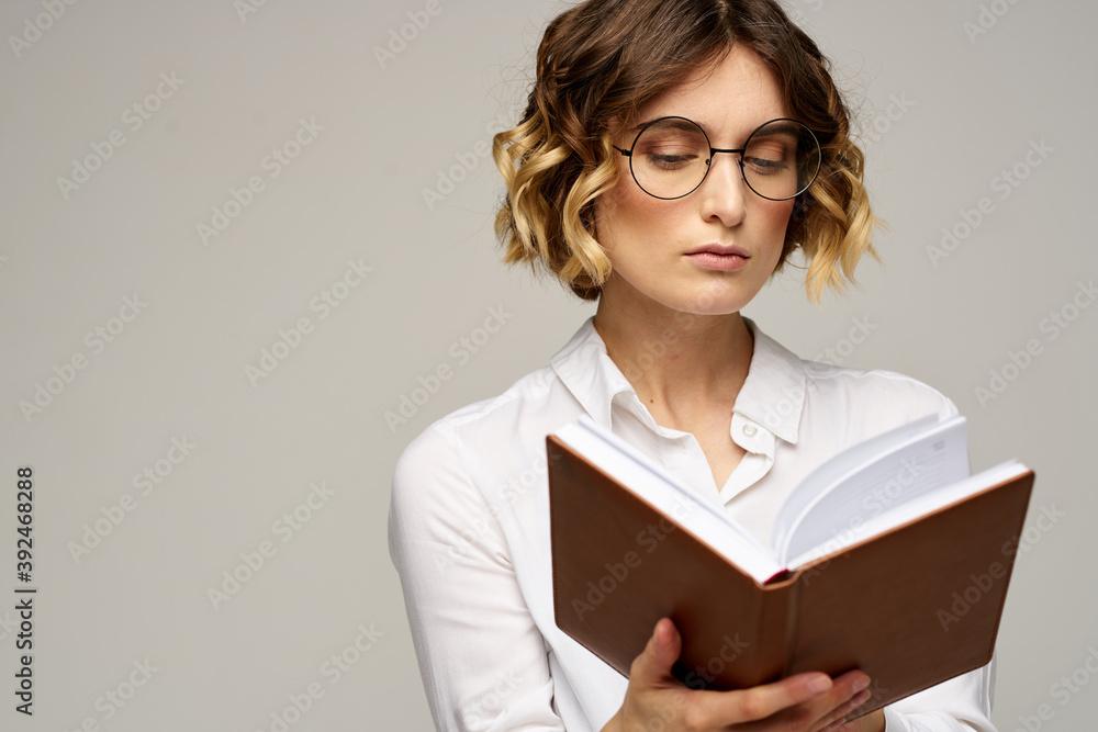 Business woman with notepad and glasses on a light background hairstyle success emotions Business woman with notepad and glasses on a light background hairstyle success emotions