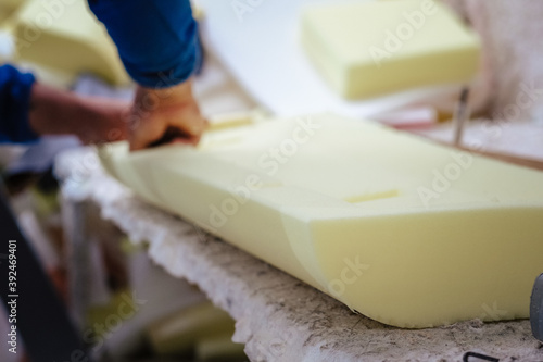 Vertical shot of a furniture maker shaping an upholstery foam