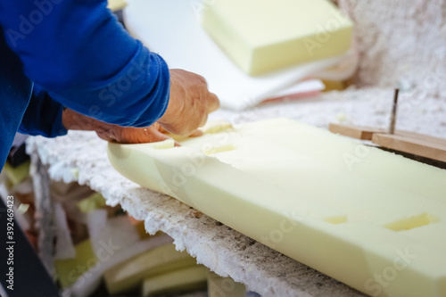Vertical shot of a furniture maker shaping an upholstery foam