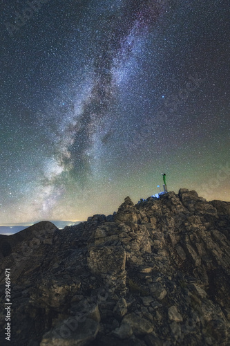 Climber stands still on the summit of Mt Olympus pointing the Milky Way Galaxy
