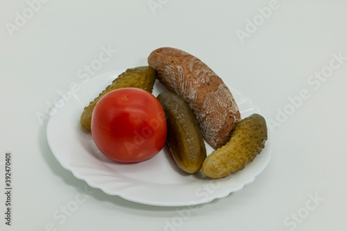 a slice of black bread, cucumbers and tomatoes on a plate