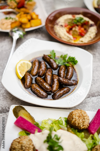 Makanek (Lebanese Sausages) served in a hot pomegranate molasses with lemon and parsley