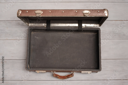 Retro style brown open empty suitcase on the wooden floor background.