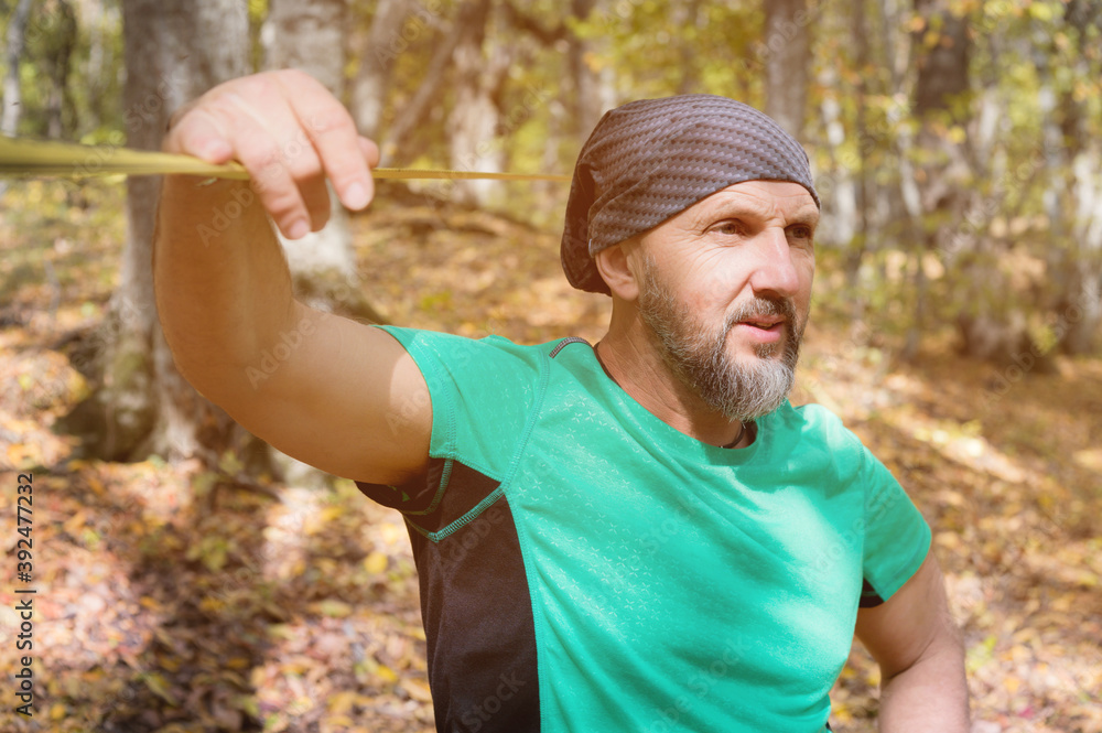 Portrait of a bearded man in age stands near a taut slackline in an autumn forest Portrait of a bearded man in age stands near a taut slackline in an autumn forest