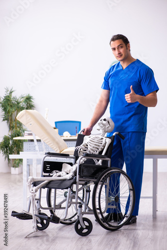 Young male doctor and skeleton in wheel-chair