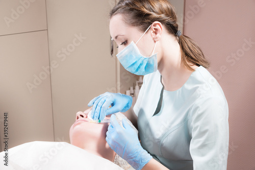 Professional beautician conducts an injection of botox or hyaluronic acid to a client in a beauty salon