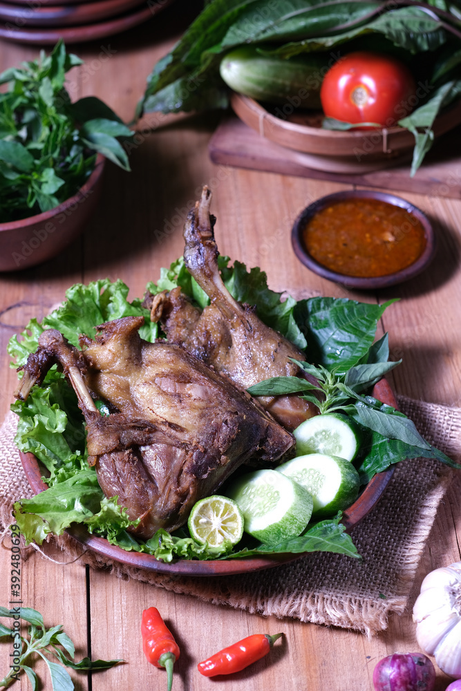 Bebek Goreng, popular Indonesian dish of deep-fried duck; served with raw fresh green vegetables and chili paste. Bebek Goreng, popular Indonesian dish of deep-fried duck; served with raw fresh green vegetables and chili paste.