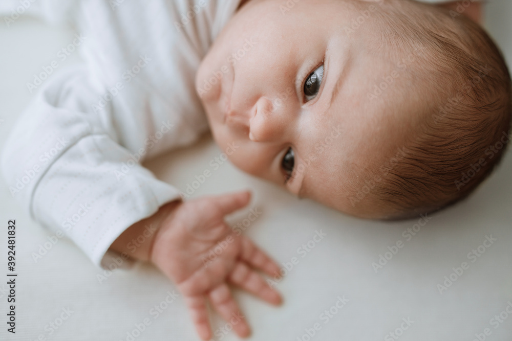 Adorable baby in a white sunny bedroom. Newborn baby is resting in bed. Family morning at home. Adorable baby in a white sunny bedroom. Newborn baby is resting in bed. Family morning at home.