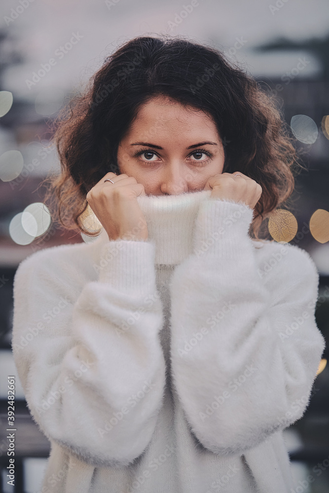 Portrait of a woman pulling her white sweater over head
