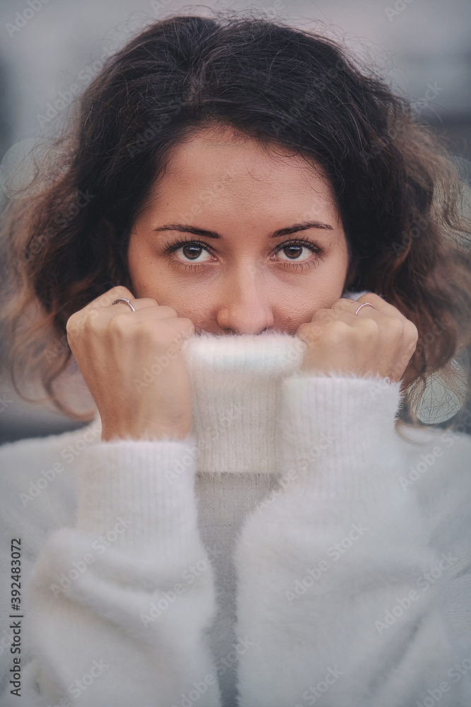 Portrait of a woman pulling her white sweater over head