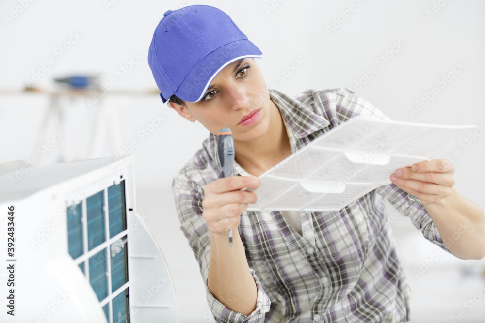 woman working on air conditioning unit woman working on air conditioning unit