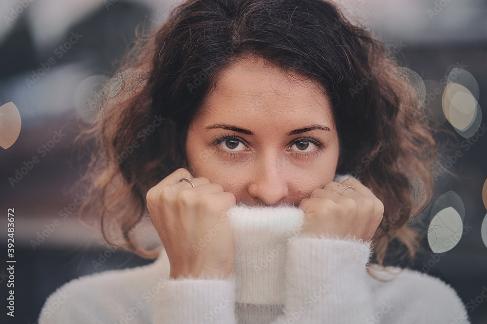 Portrait of a woman pulling her white sweater over head
