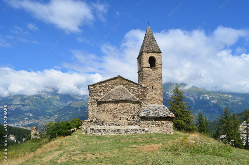 Saint-Pierre d'Extravache Church, fields and alpacas. in the background of the Vanoise National Park, France