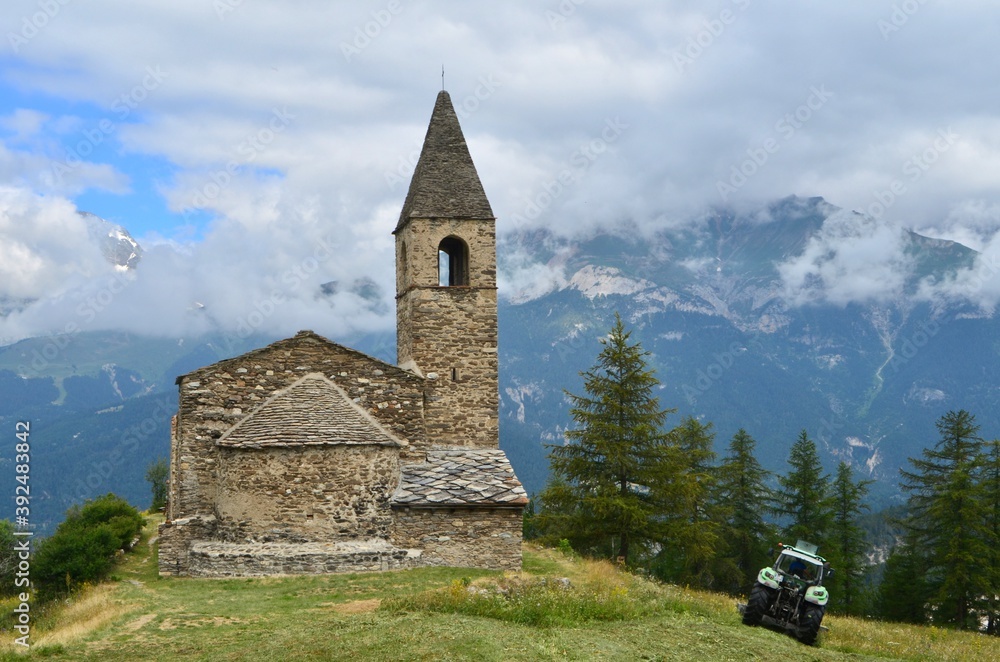 Saint-Pierre d'Extravache Church, fields and alpacas. in the background of the Vanoise National Park, France