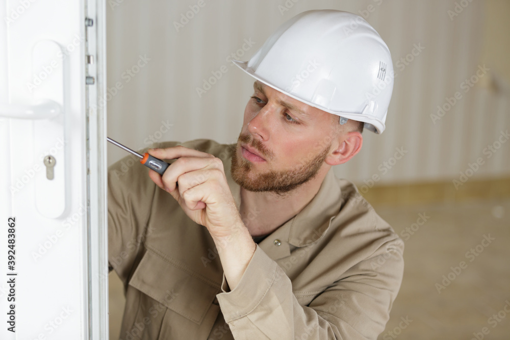 young male contractor using screwdriver on a door lock mechanism young male contractor using screwdriver on a door lock mechanism