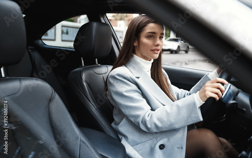Elegant woman driving her car, looking at rear window. Businesswoman driver going on a meeting © Liubov Levytska