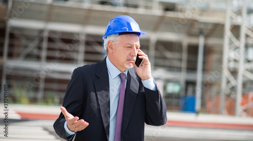 Architect talking on the phone in front of construction site