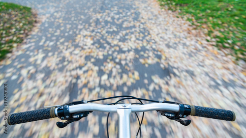 Bycicle ride: point of view of the cyclist, with handlebars with no hands at the bottom, and blurred moving track on the background