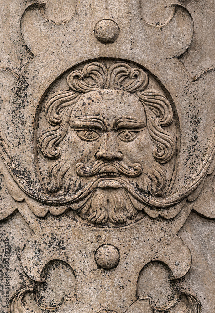 Ancient carved stone face in a flat wall commonly revered in ancient cultures.