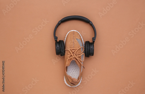 Sports shoe with stereo headphones on brown background. Getting ready for training. Top view. Flat lay