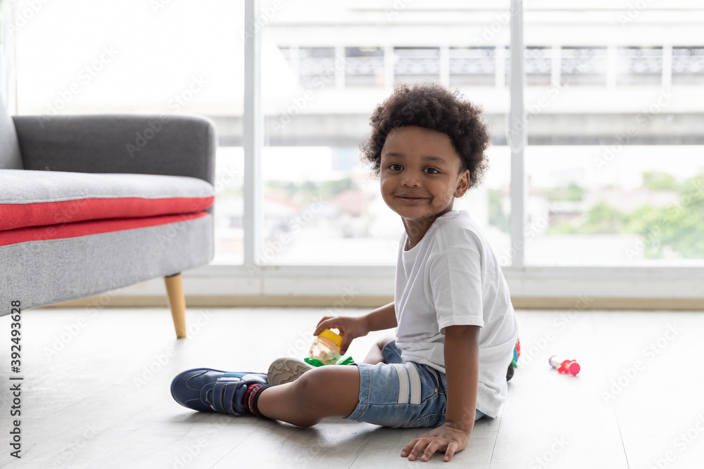 Adorable Afro little boy, boy looking at the camera, cute African American little boy playing with toy cars on the ground at home. kid, playing, holiday concept
