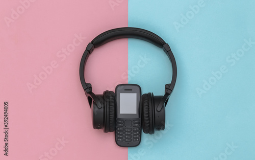 Push-button telephone with stereo headphones on pink blue background. Top view