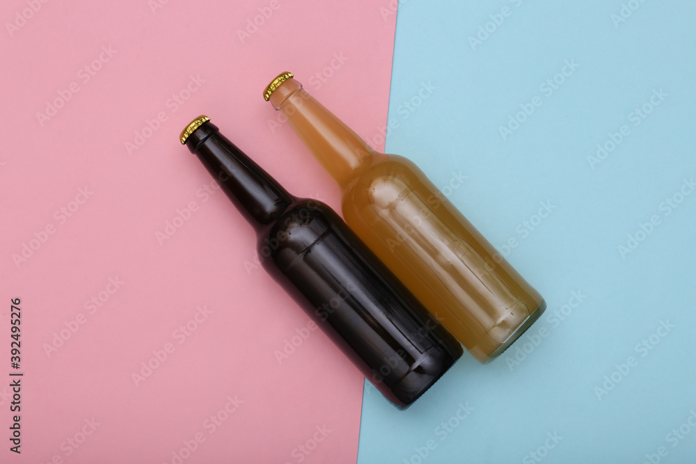 Bottle of light and dark beer on pink blue background. Top view Bottle of light and dark beer on pink blue background. Top view