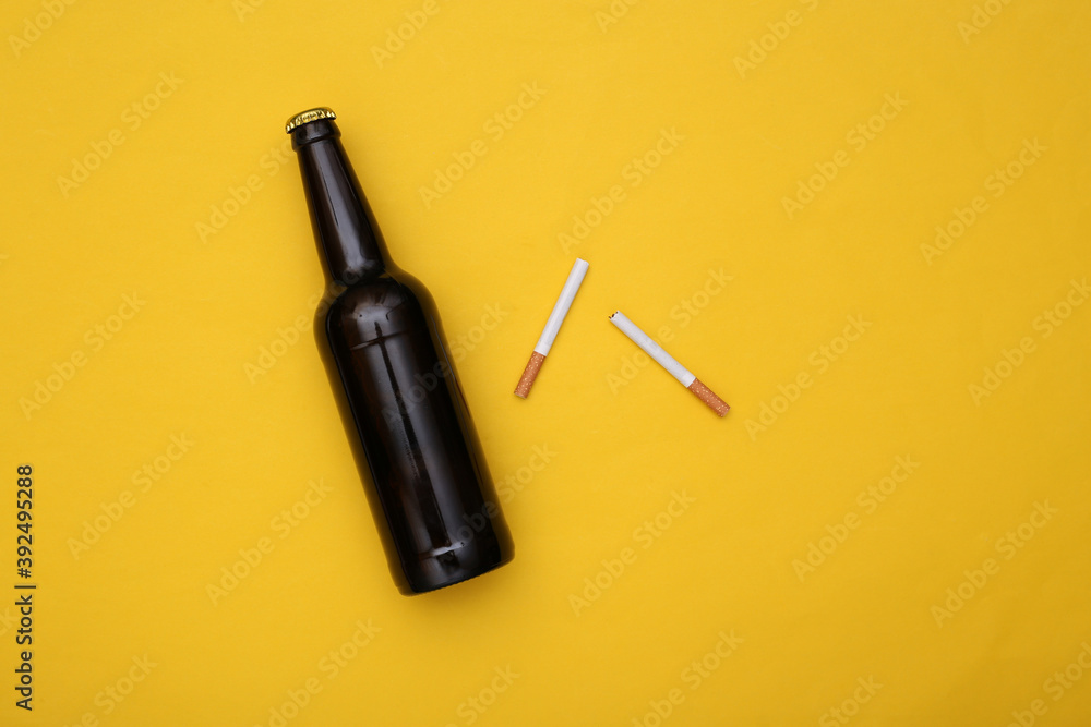 Naklejka premium Beer bottle and cigarette on yellow background. Alcohol and nicotine addiction