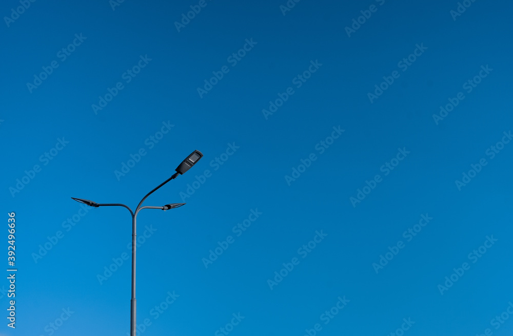 The street light pole with a blue sky background - Automatic street twin lamp against the blue sky with copy space The street light pole with a blue sky background - Automatic street twin lamp against the blue sky with copy space