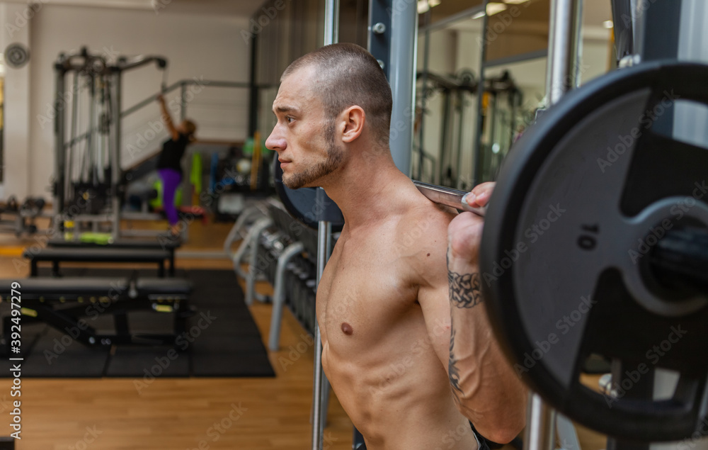 Portrait of a young muscular man with a barbell on his shoulders in the gym Portrait of a young muscular man with a barbell on his shoulders in the gym