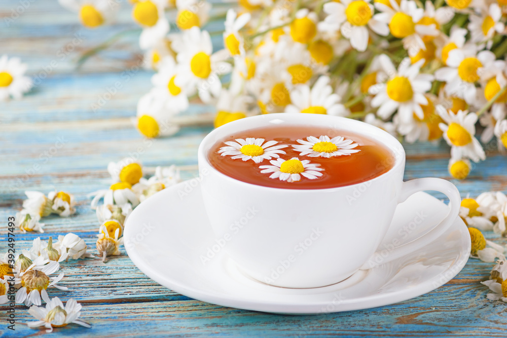 Daisy flowers in a white cup of tea, chamomile herbs on wooden background. Herbal medicine. Healthy lifestyle concept. Daisy flowers in a white cup of tea, chamomile herbs on wooden background. Herbal medicine. Healthy lifestyle concept.
