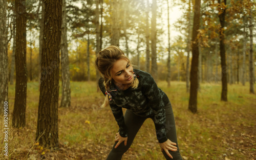 Tired sport fit woman with pigtails resting after jogging in the autumn forest. Healthy lifestyle concept © splitov27