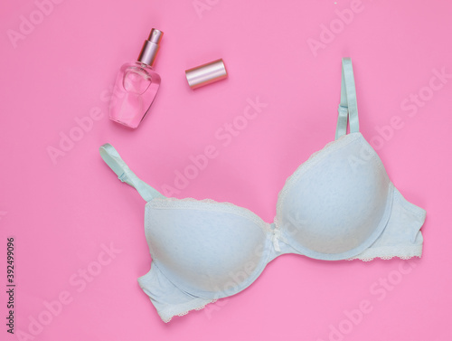 Stylish bra, perfume bottle on pink pastel background. Top view. Beauty and fashion minimalistic still life