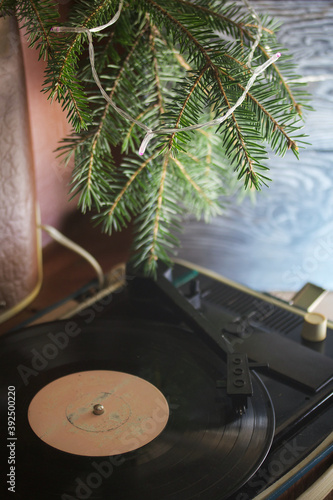 Old turntable. Nearby there are spruce branches and burning festive garlands. Against the background of pine boards.